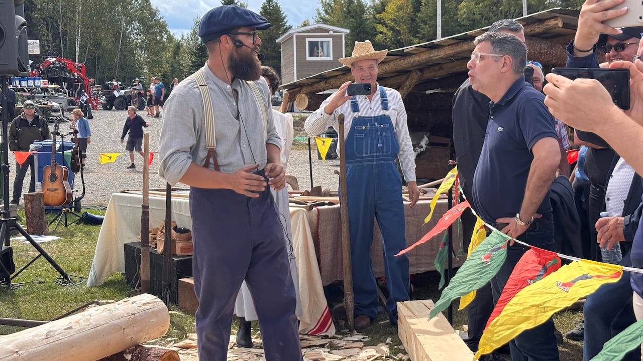 A man talks to lumberjacks at a festival in Saint-Pamphile.
