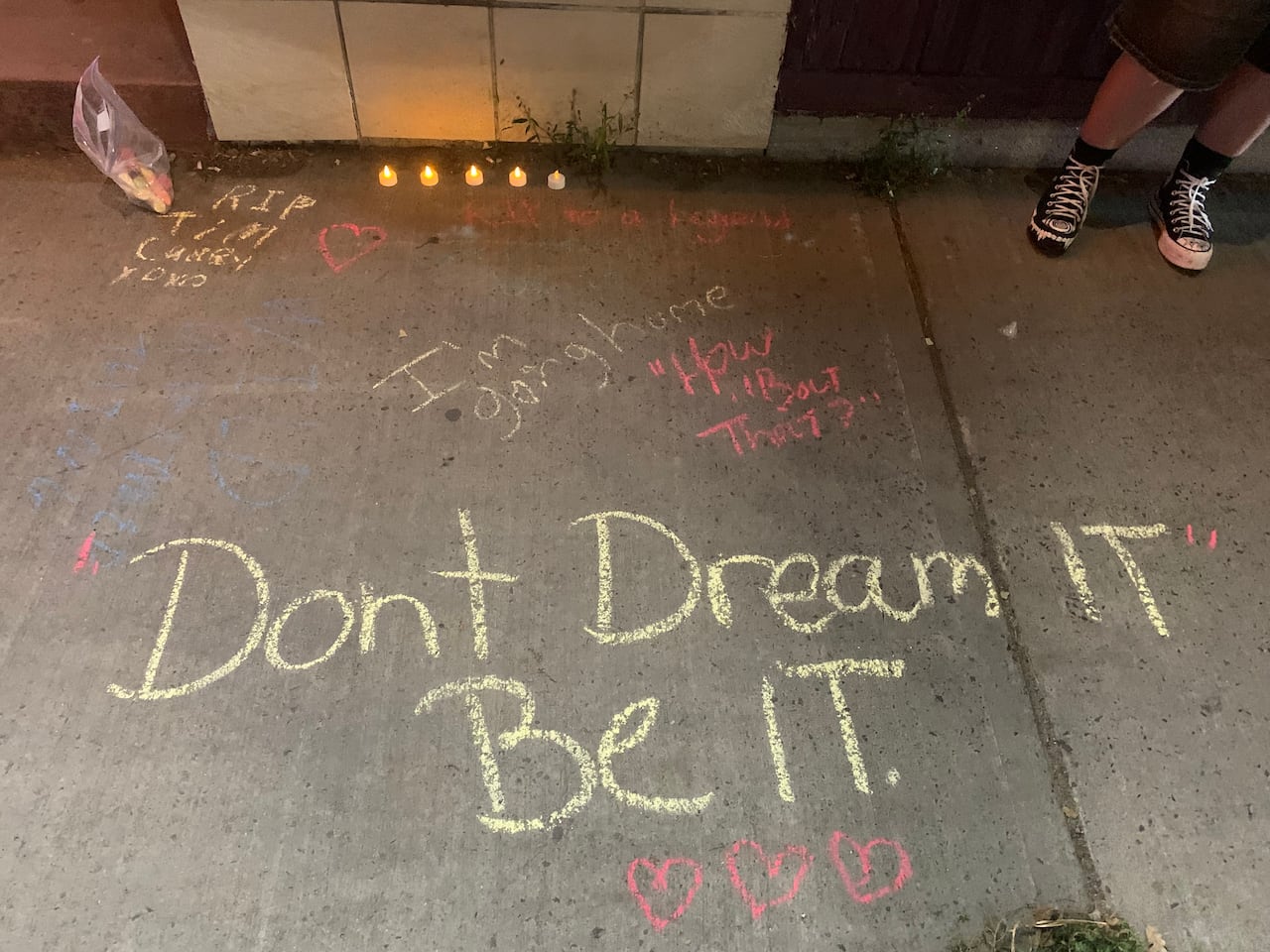 Candles lined the pavement, with messages written by fans in red, yellow, and blue chalk.