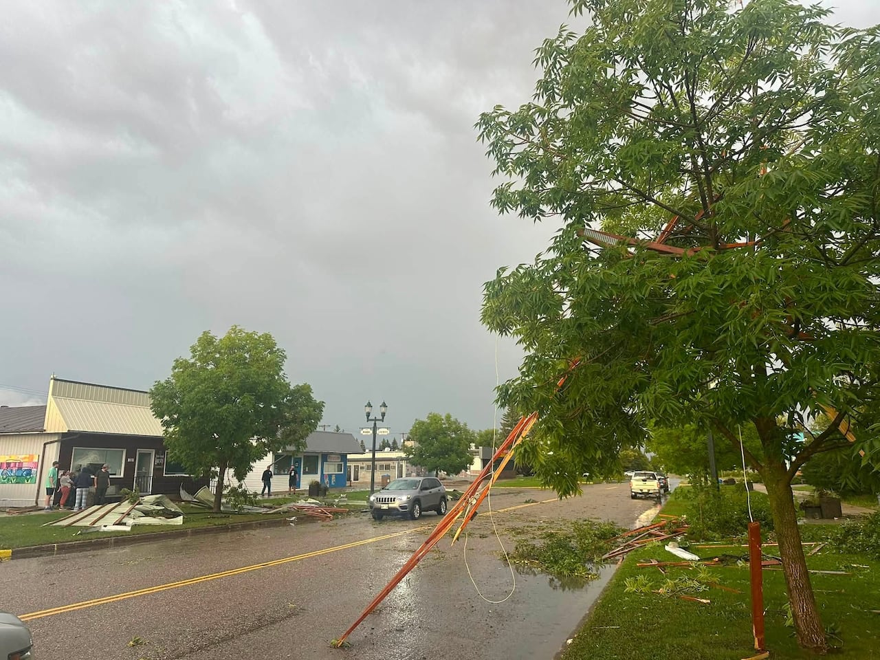 A street is shown with debris and broken tree branches on the ground.