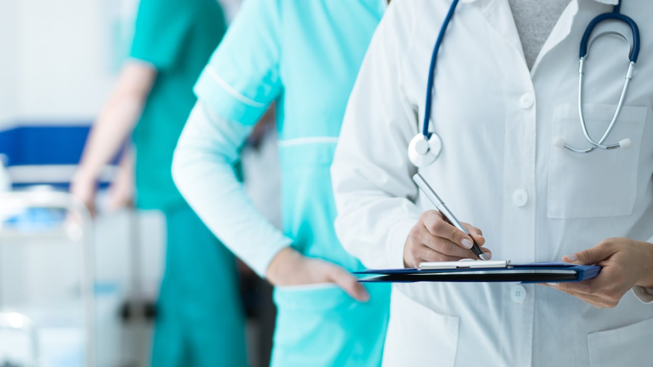 Medical staff working at the hospital: doctor and nurse checking a patient's medical record on a clipboard, healthcare and medical exams concept.