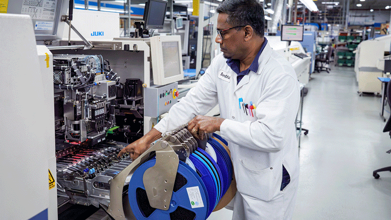 An animation gif of four images shows workers assembling printed circuit boards during various stages of the process at a facility.
