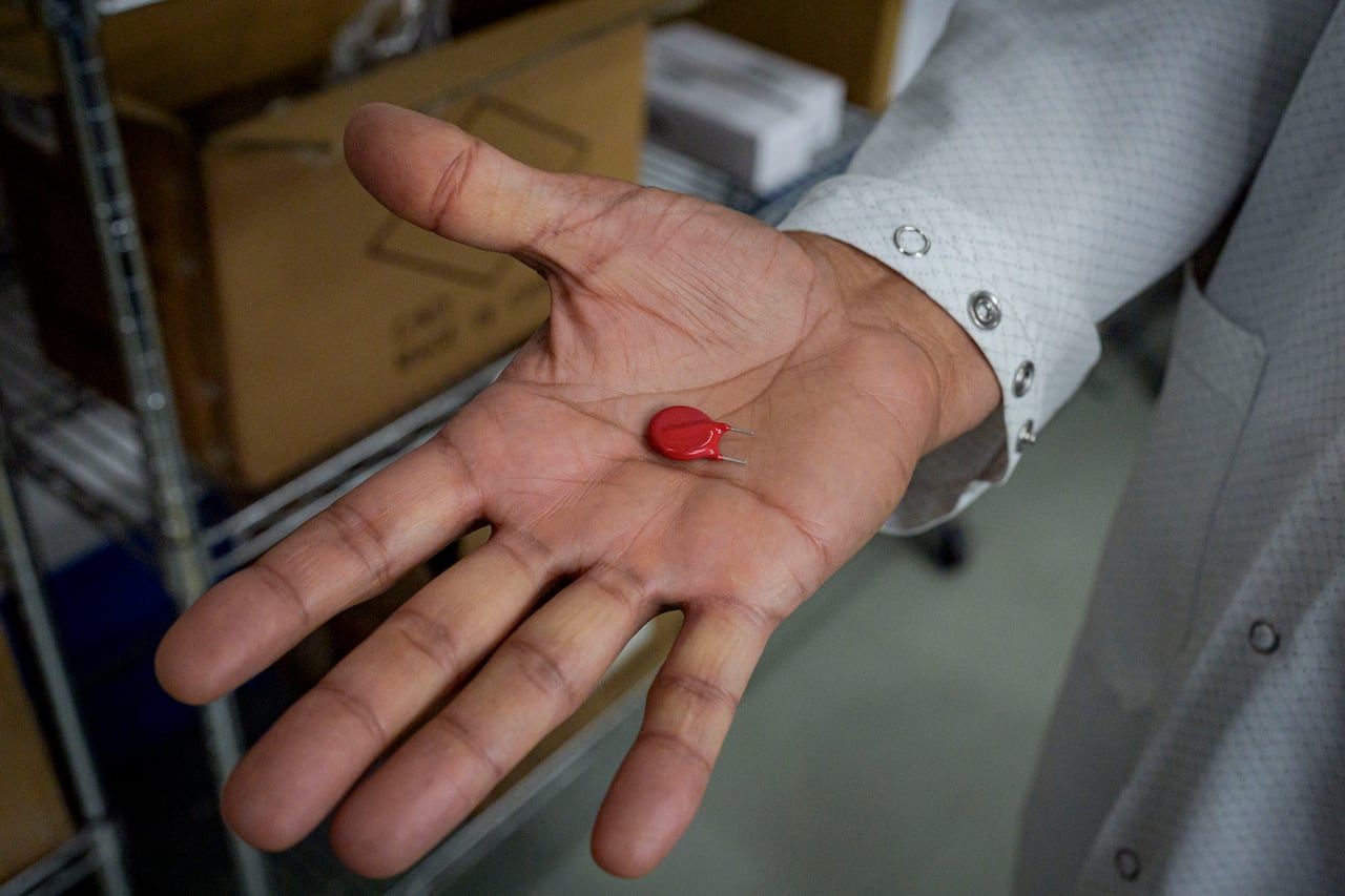 A red component in the palm of a person's hand.