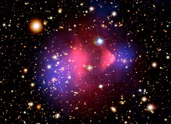Two galaxy clusters after a collision, with the mass (blue) separated from the visible matter (pink). It is among the clearest evidence that dark matter exists, and among the least informative about what it actually is (Credit : X-ray NASA/CXC/CfA/M. Markevitch et al.; Optical NASA/STScI; Lensing map NASA/STScI, ESO WFI, Magellan/U.Arizona/D. Clowe et al.)