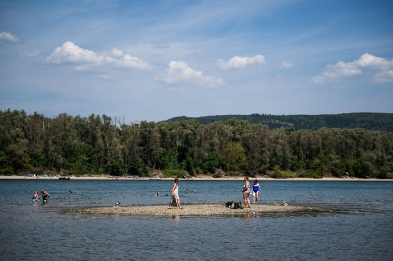People spend time on a newly exposed island due to the low water level of the Danube River in Kisoroszi, Hungary, August 1, 2026. REUTERS/Marton Monus