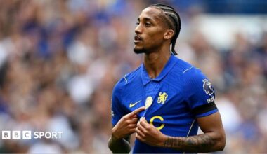 Joao Pedro points at the World Champions badge of Chelsea's shirt