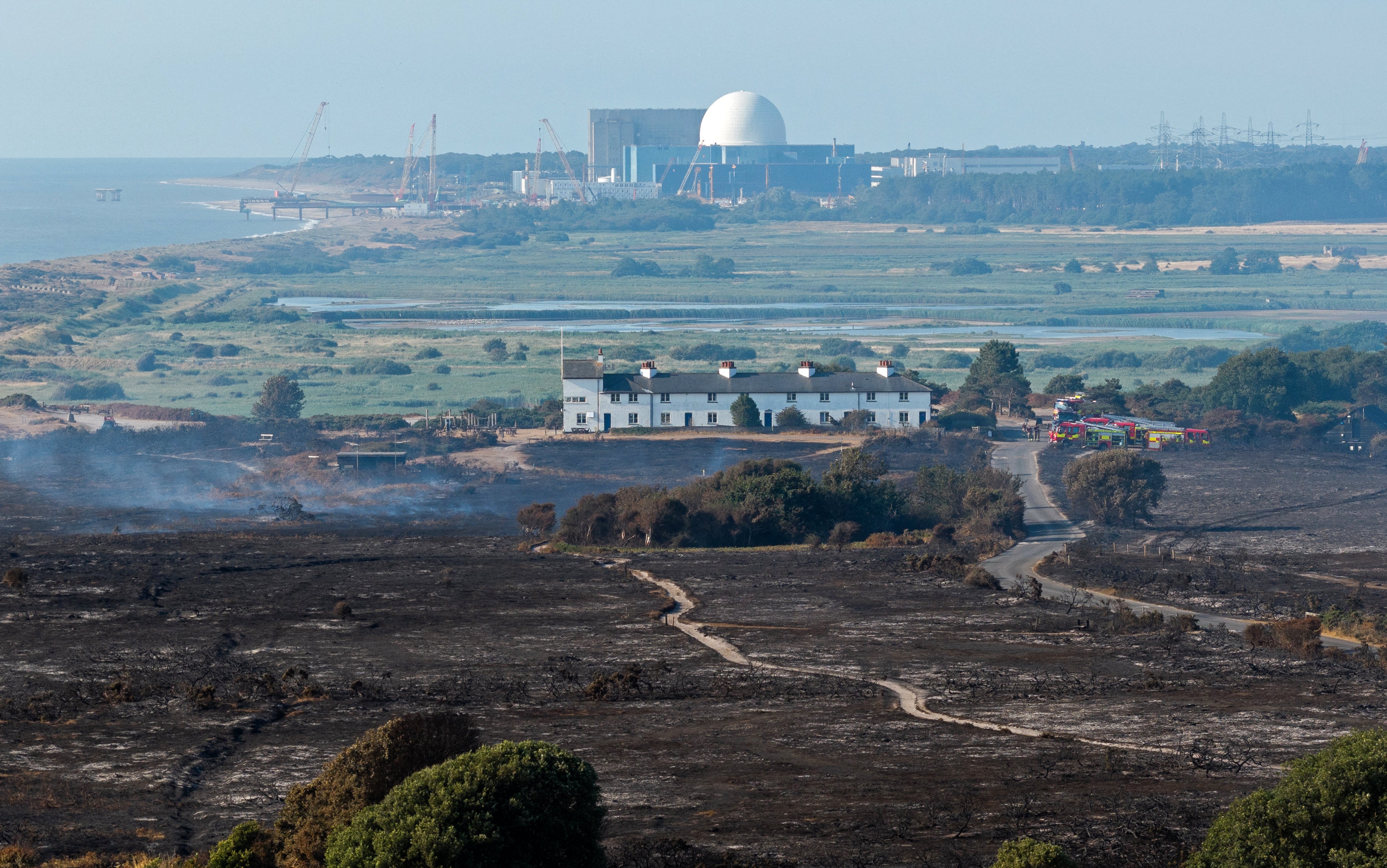 Scorched land following a wildfire at Dunwich Heath on 31 July, with the Sizewell nuclear power station in the background