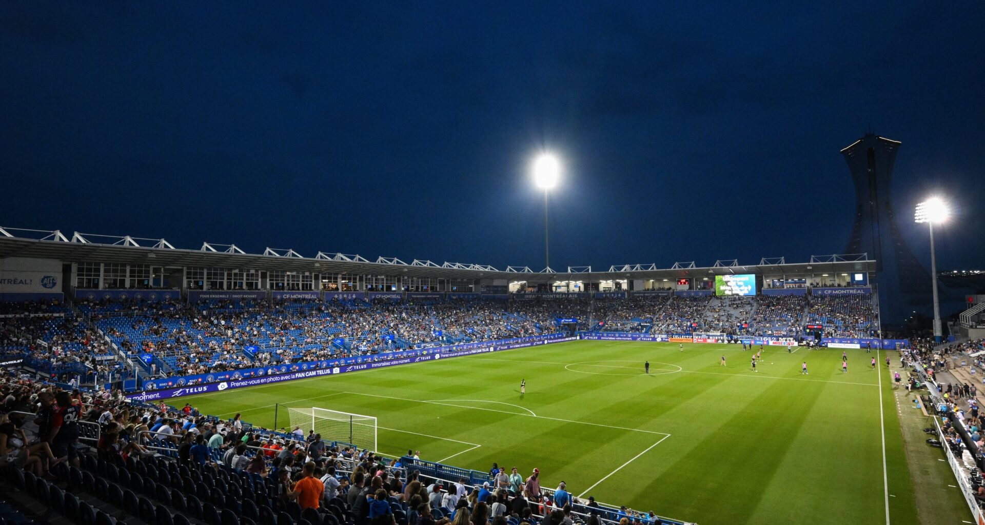 Saputo Stadium at night with Montreal's Olympic Stadium visible in the background