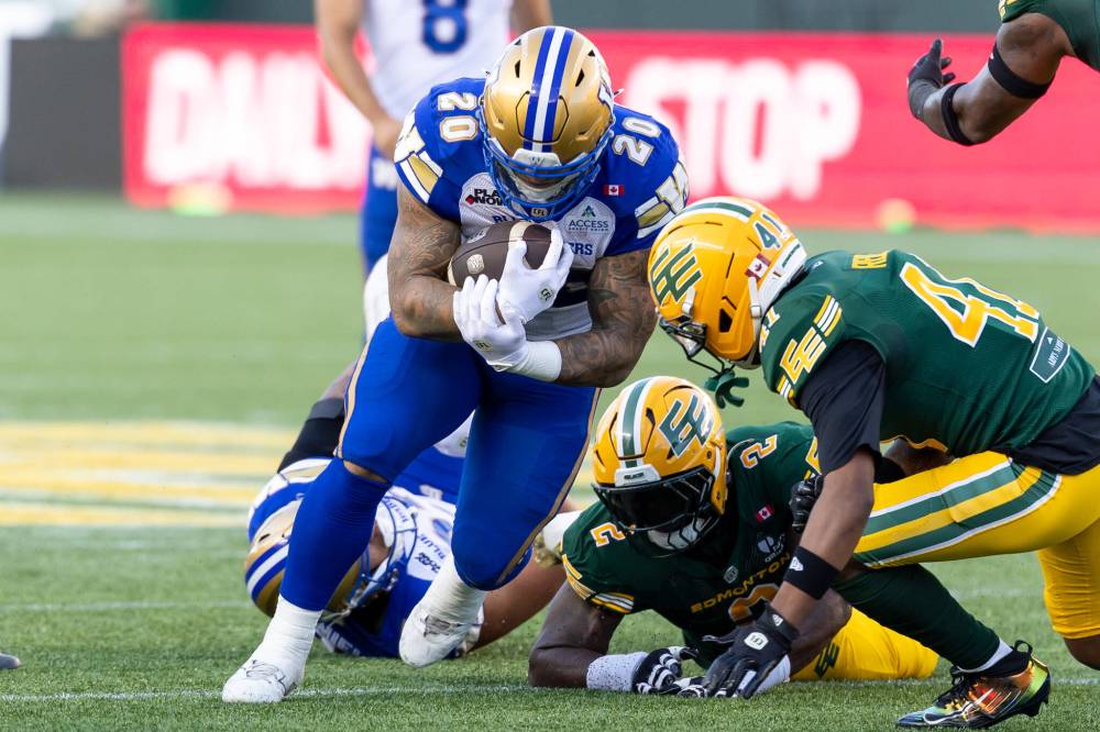 Winnipeg Blue Bombers' Brady Oliveira (20) rushes with the ball against the Edmonton Elks defence during first half CFL football action in Edmonton on Friday, August 21, 2026. THE CANADIAN PRESS/Timothy Matwey