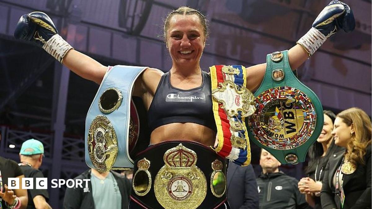 Ellie Scotney smiles and stretches her arms wide as she shows off the WBO, WBA, IBF and WBC super-bantamweight belts
