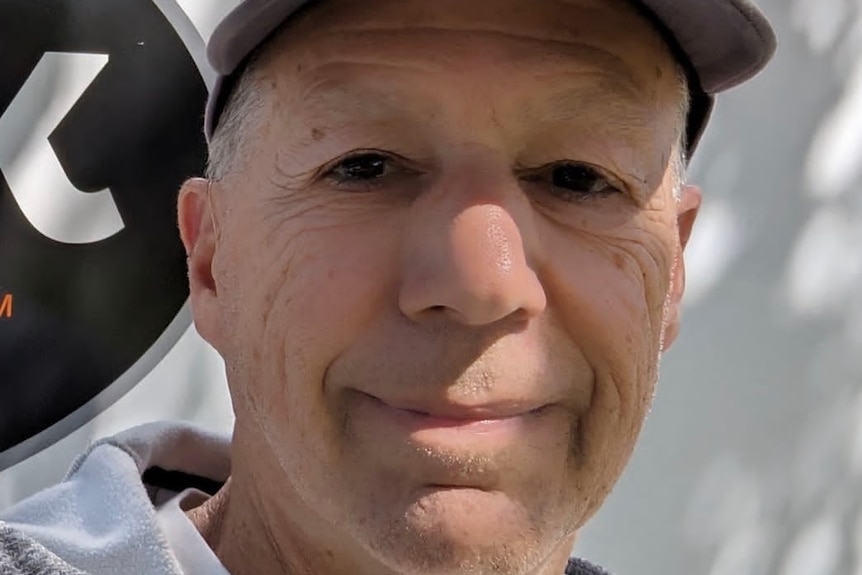 A close up of a man's face, wearing a cap.
