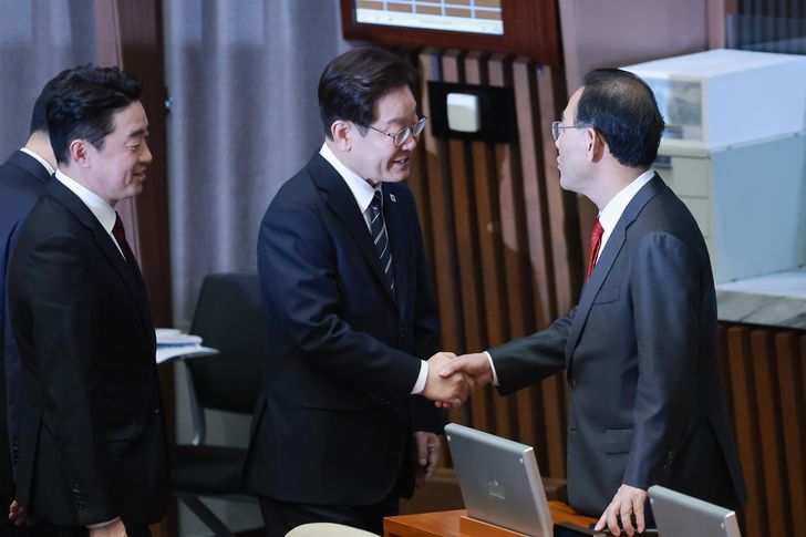 President Lee Jae Myung, center, shakes hands with Rep. Joo Ho-young, then deputy speaker of the National Assembly, after giving a speech on the government's first supplementary budget bill in Seoul, April 2. Korea Times photo by Min Kyung-seok 