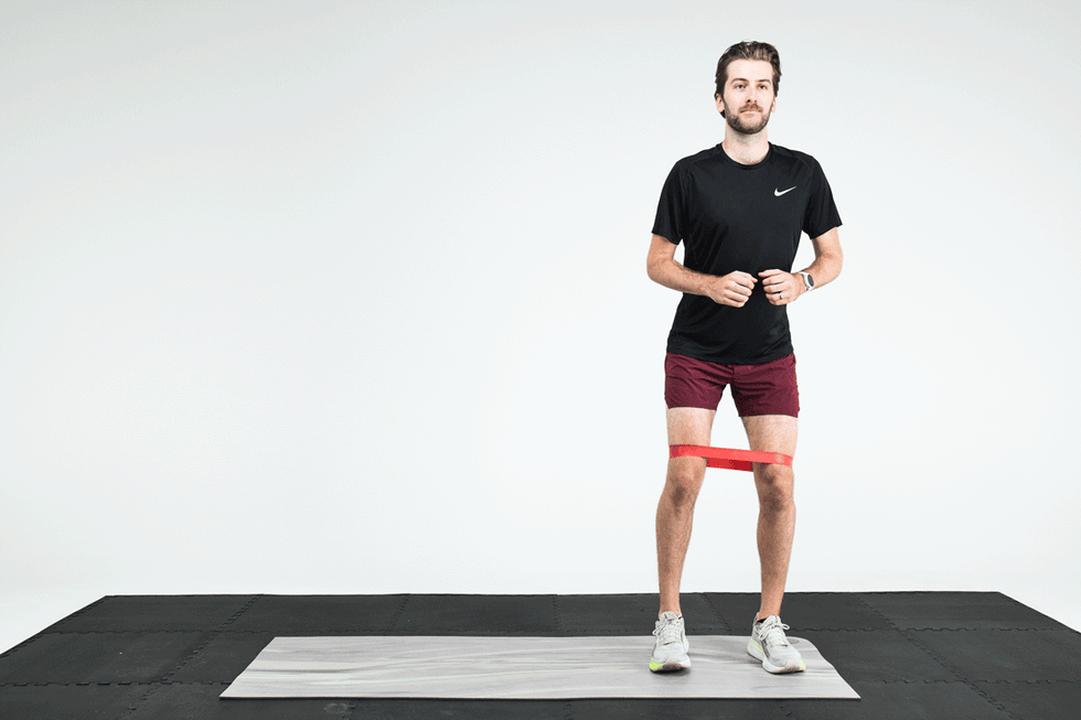 Man demonstrating an exercise with a resistance band around his thighs on a gym mat. Man demonstrating an exercise with a resistance band around his thighs on a gym mat.