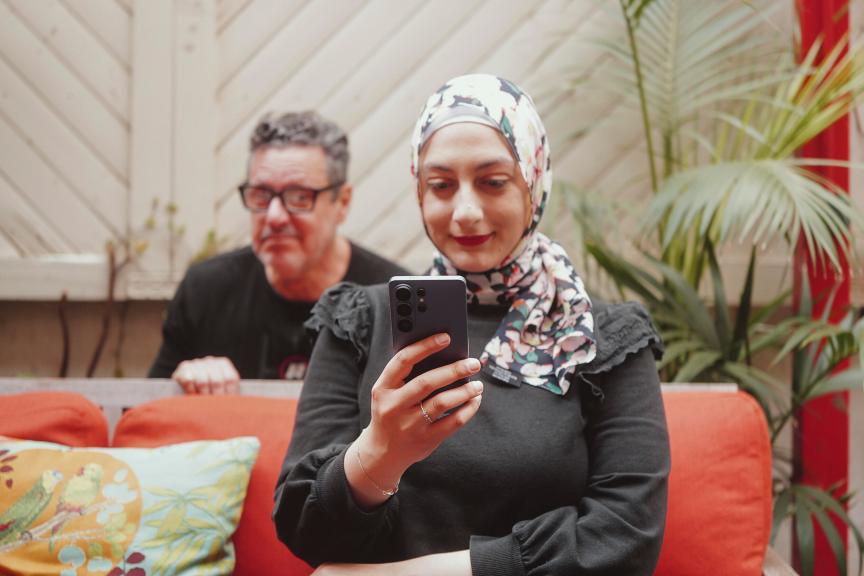 A man looking over the shoulder of a woman using her Galaxy S26 Ultra
