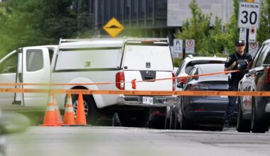 A white pickup truck and police vehicles are behind orange crime-scene tape.