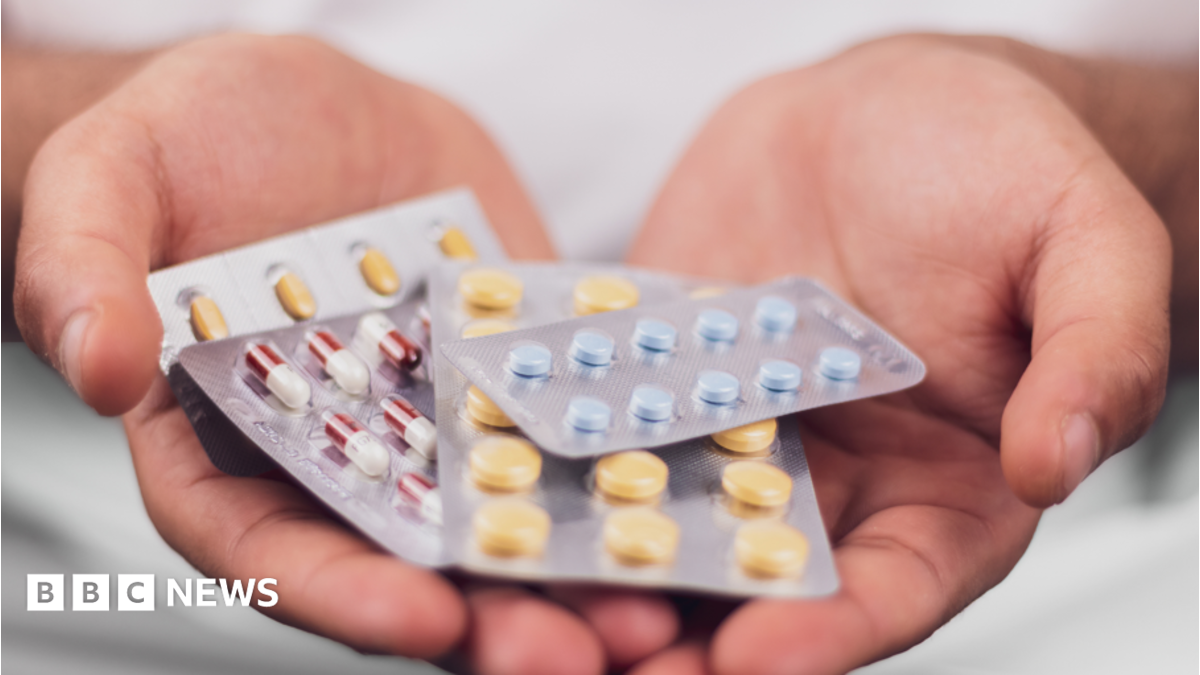 A hand holding a series of pharmaceutical drugs in packets.