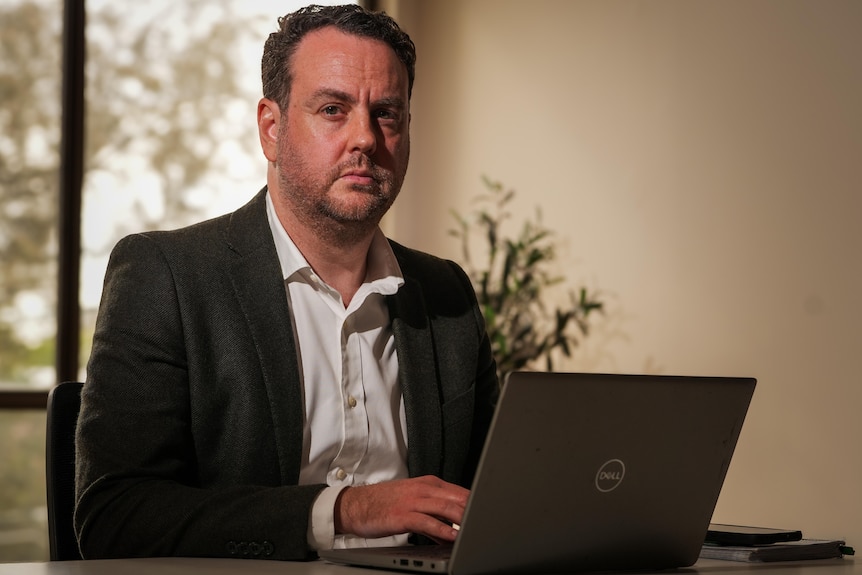 A man seated in front of a laptop.