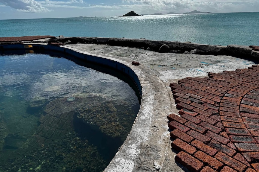 A swimming pool at the beach that is in disrepair.