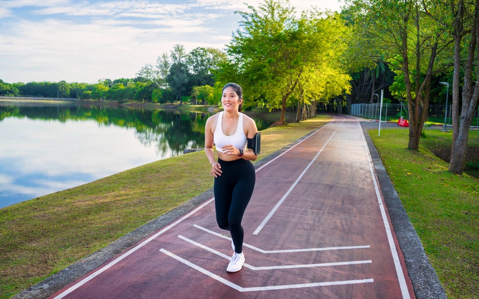 Young asian sports woman runner running in the public park. Happy athletic woman jogging in the morning. Healthy fitness female exercising at outdoor park. Young asian sports woman runner running in the public park. Happy athletic woman jogging in the morning. Healthy fitness female exercising at outdoor park.