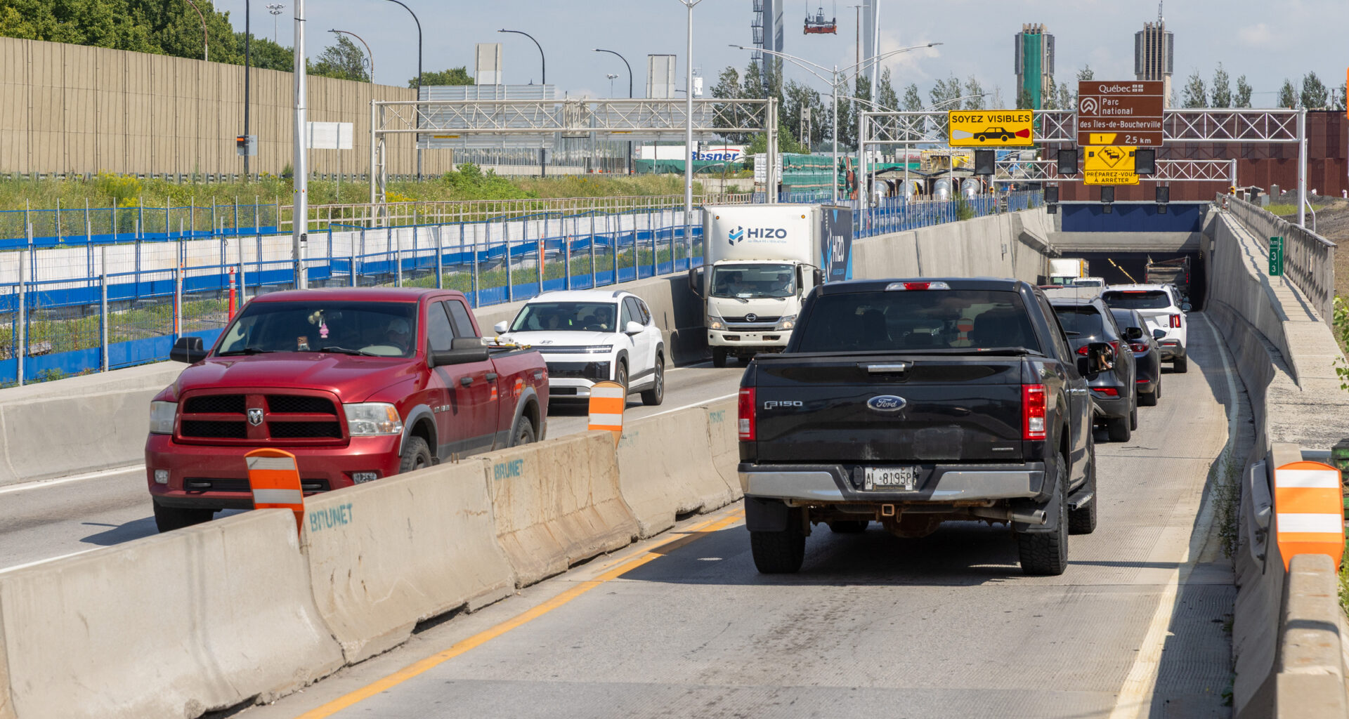 Traffic goes through a construction site near the mouth of a tunnel.