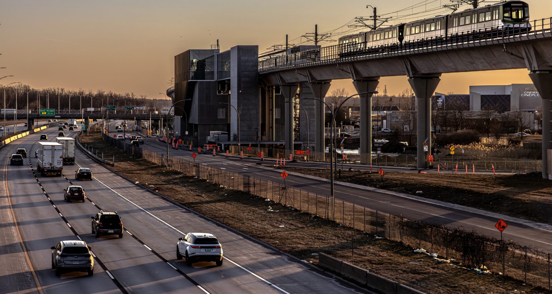 A light rail train travels an elevated track at sunset.