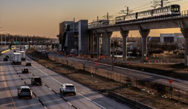 A light rail train travels an elevated track at sunset.