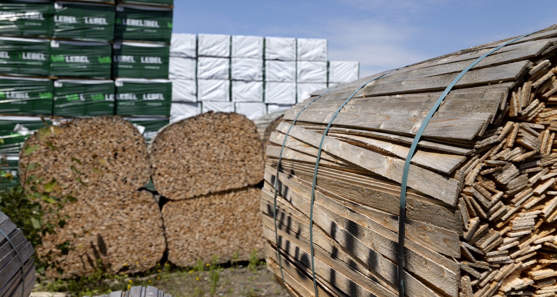 Stacks of building materials outdoors, including forence.