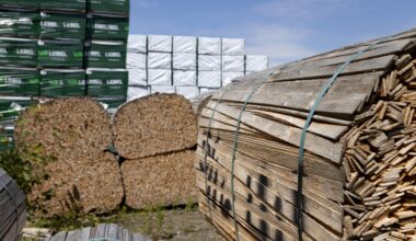 Stacks of building materials outdoors, including forence.
