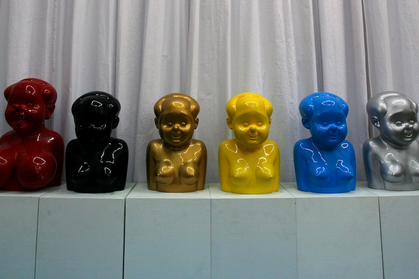 Eight sculptures in different colours in a line.