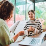 Rearview female recruitment reading and checking resume in hands interviewing and hiring woman candidate for joи near laptop in office with glass windows - stock photo