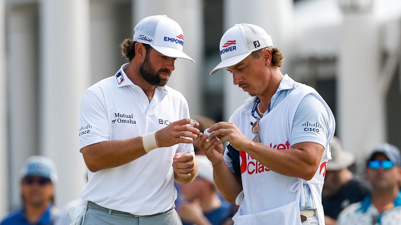 Cameron Young and his caddie look at a golf ball
