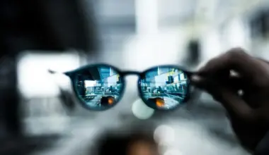 A hand holding smart glasses, viewing a cityscape.