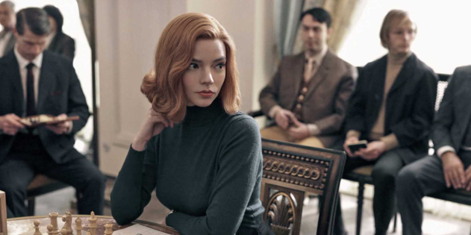 Beth sitting at a table playing chess in The Queen's Gambit.