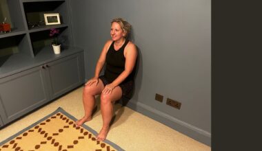 Kat doing wall sit exercise in living room at home