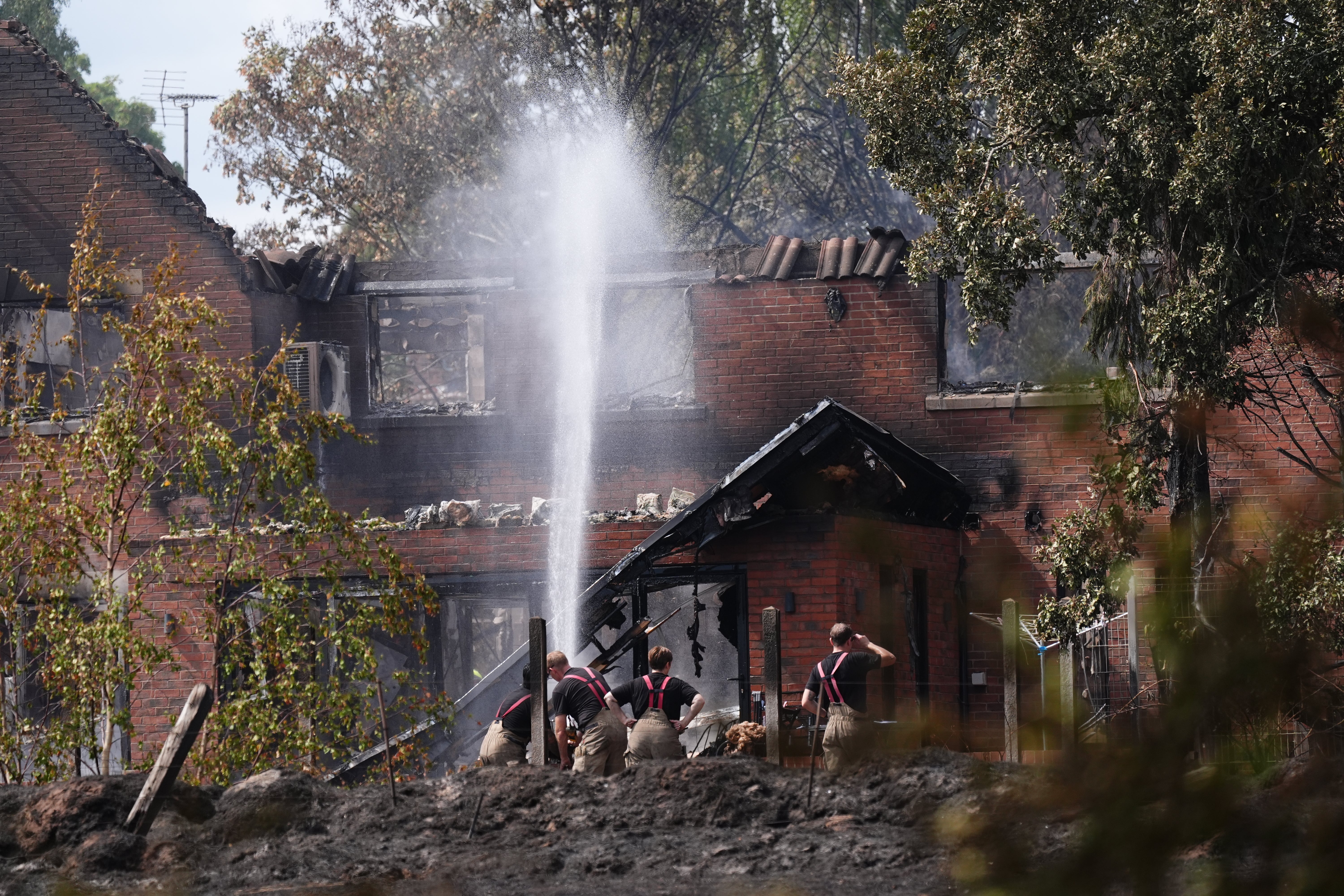 Firefighters spraying water onto the burnt out remains of a house following a huge blaze in Stourbridge