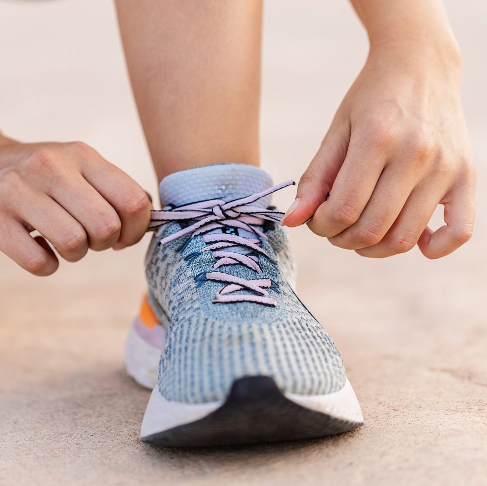female jogger hands tying laces of her sport shoes close up view of female jogger tying laces of her sport shoes before running exercise routine. motivation, healthy lifestyle and fitness concept.