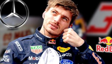 Verstappen in Red Bull race suit looking at Mercedes logo with blurred background of Red Bull garage and No.3