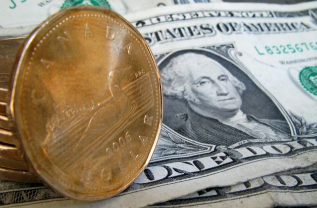 Canadian dollars, or loonies, sit on American dollar bills on Sept. 20, 2007 in Montreal. THE CANADIAN PRESS/Paul Chiasson