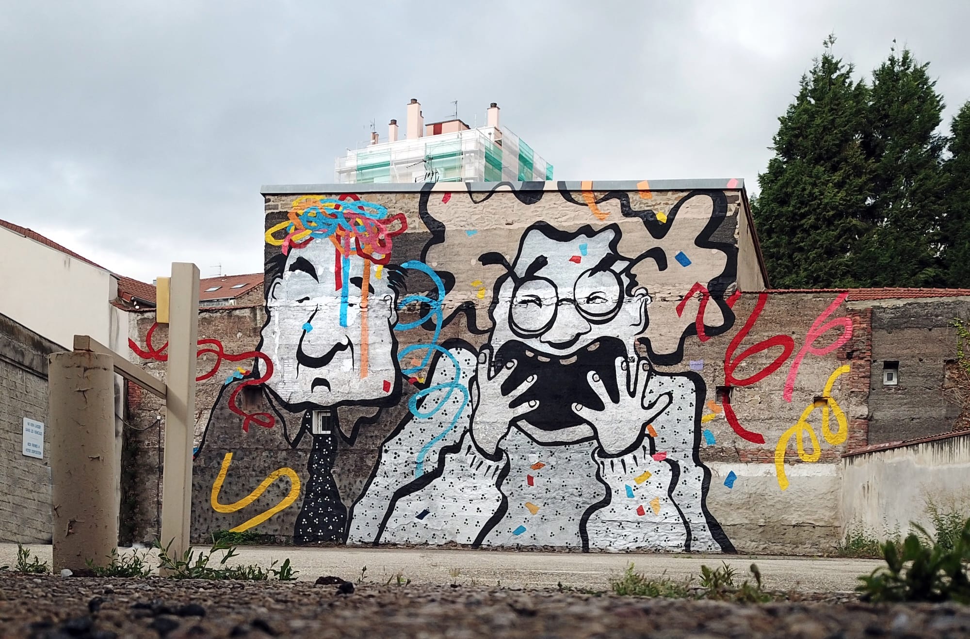 a mural by Ella & Pitr on a wall featuring two cartoonish figures, one laughing