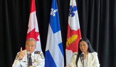 Montreal police chief sits beside Montreal mayor at press conference addressing media.