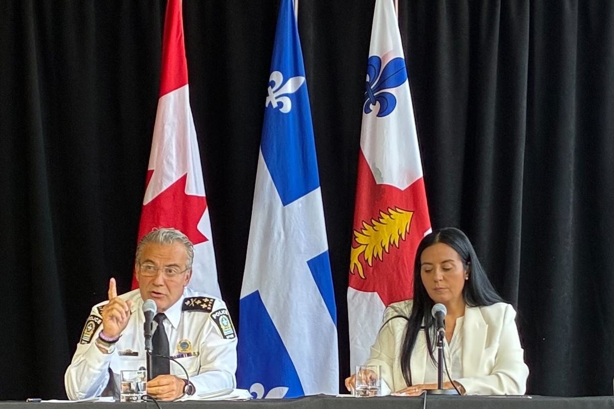 Montreal police chief sits beside Montreal mayor at press conference addressing media.