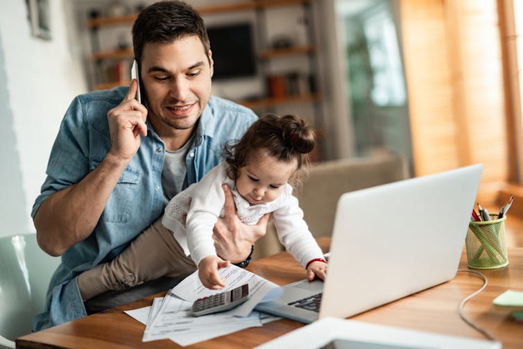 Dad on phone while holding a baby