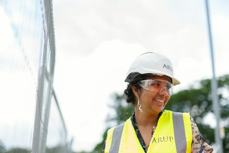 a woman wearing a high-visibility vest, hard hat and protective glasses