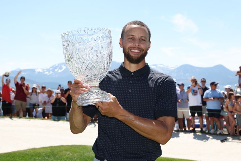 Golden State Warriors star Stephen Curry holds his trophy after winning the American Century Championship in 2023.