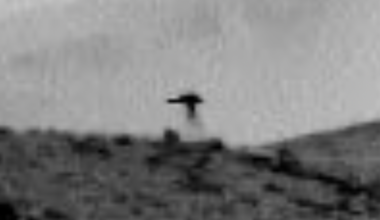 Jellyfish on Mars: Fuzzy black and white view of a rocky hill, with a dark jellyfish-like shape on top of it.