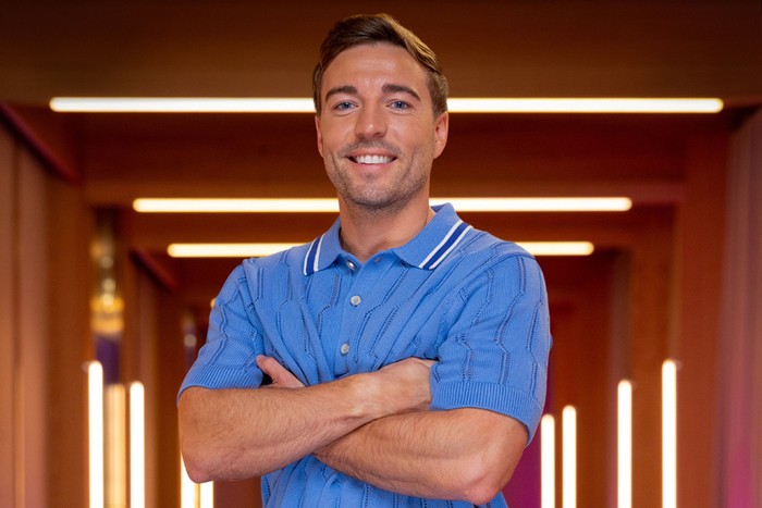 [A man stood smiling with his arms folded in front of his chest.]
