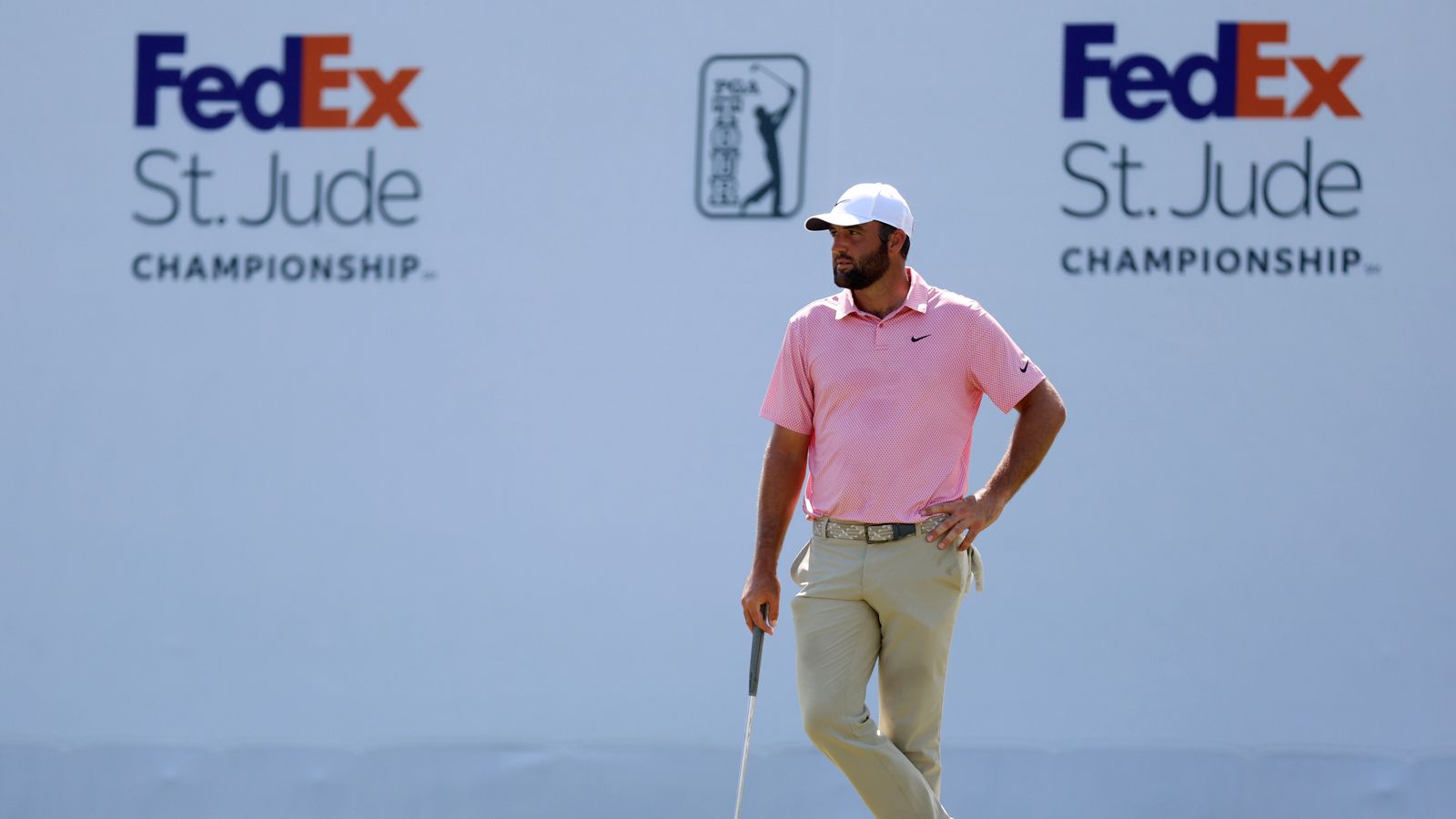 Scottie Scheffler waits on the green in front of a FedEx St. Jude Championship board