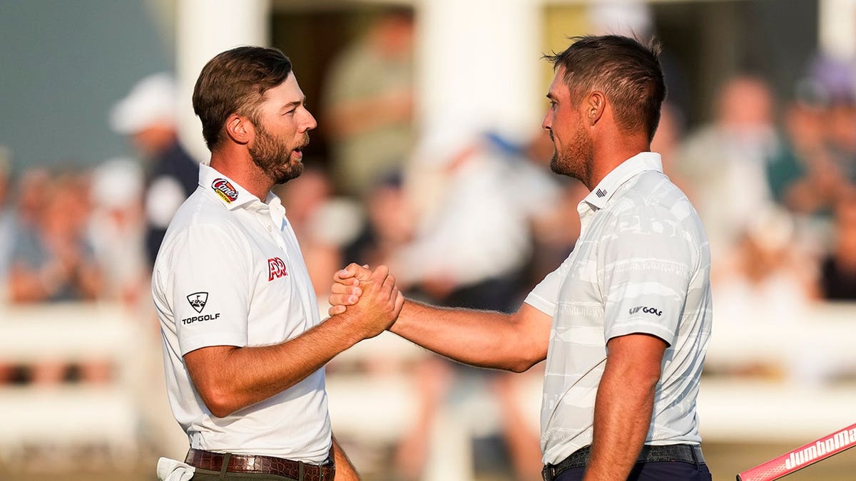 Sam Burns and Bryson DeChambeau stand on the 18th green at Royal Birkdale Golf Club.