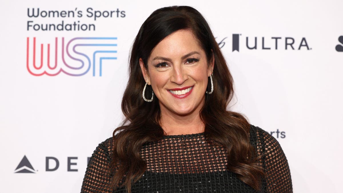 Sarah Spain smiling at a Women’s Sports Foundation event in front of a WSF backdrop.