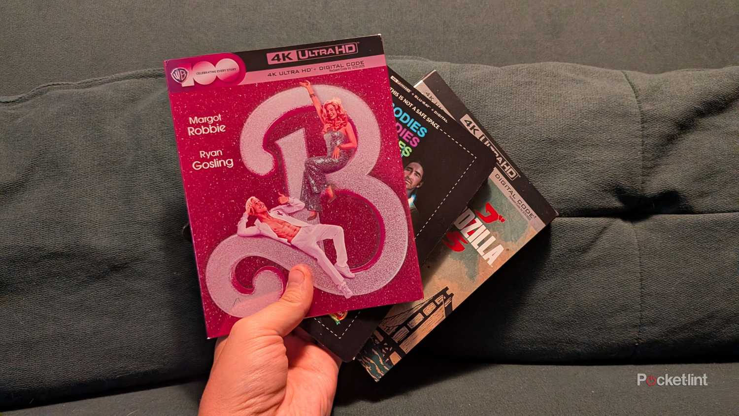 A person holding three Blu-ray slipcovers.