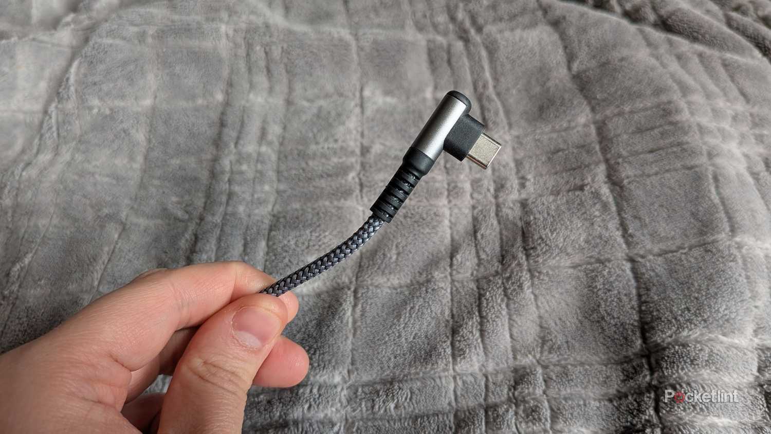 A person holding a braided USB-C cable.